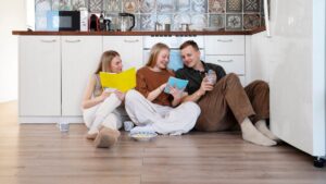 Happy family sitting on the laminate floor in the kitchen